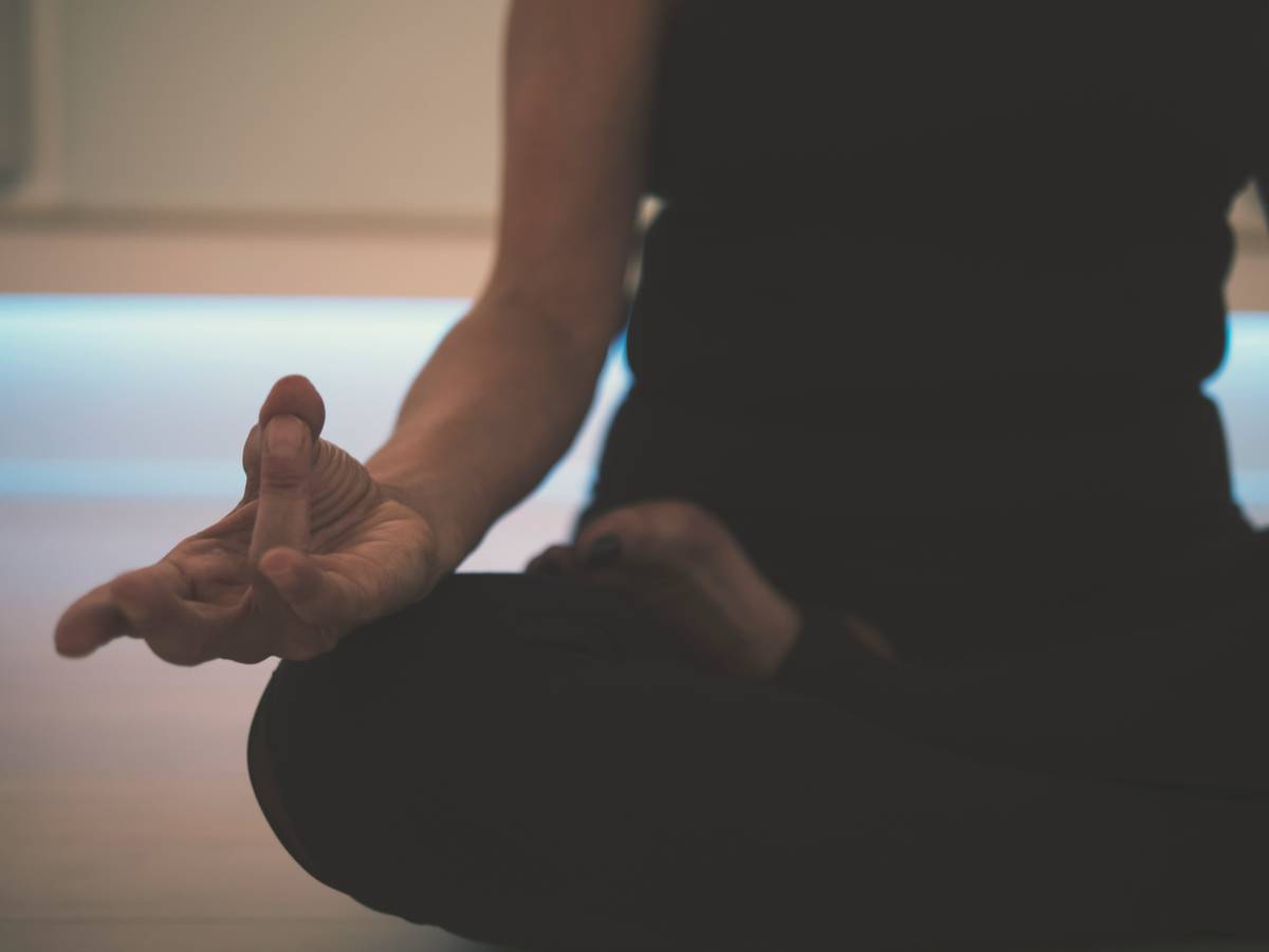 Woman practicing breath focus for anxiety while seated calmly by a lake at sunrise