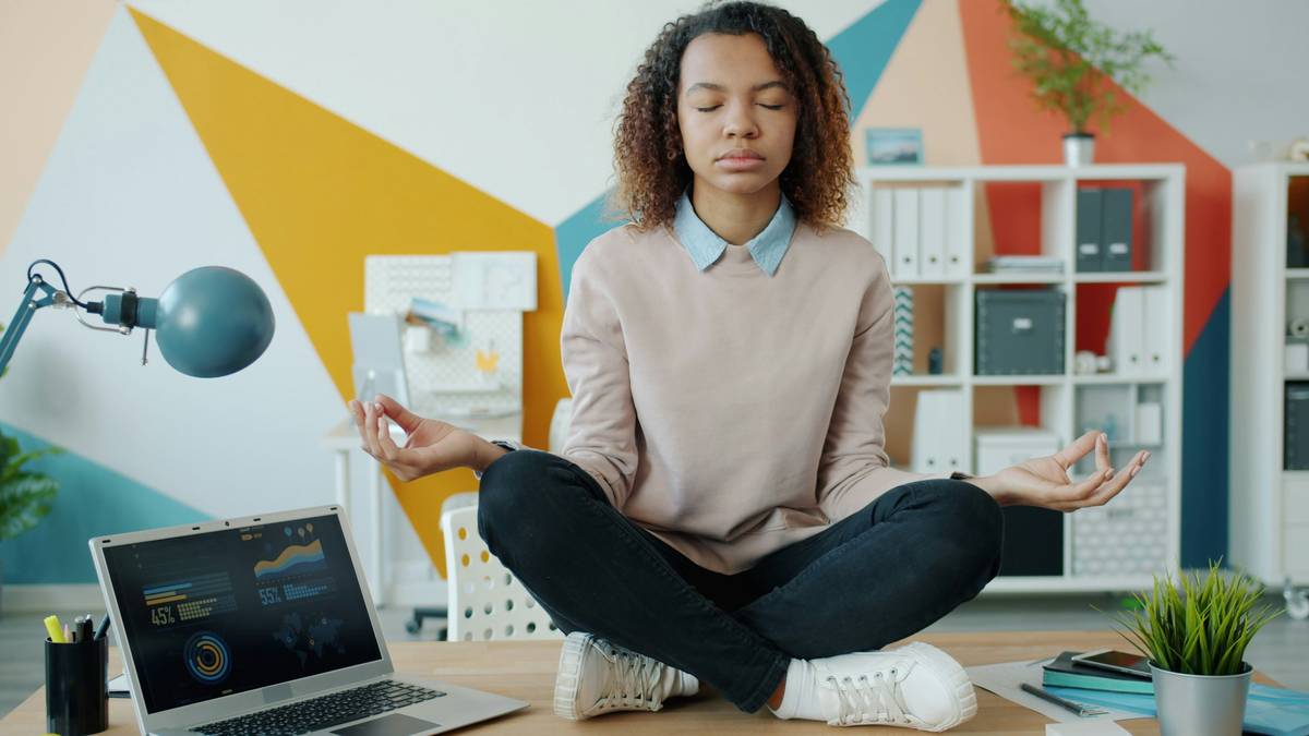 Woman practicing stress and time management with journal and timer on desk