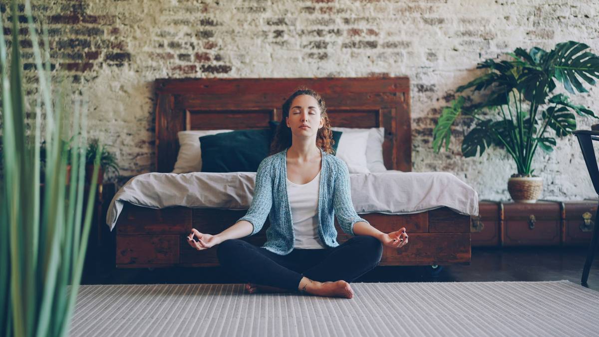 Woman sitting peacefully by a lake practicing breathing exercises showing how mindfulness helps anxiety