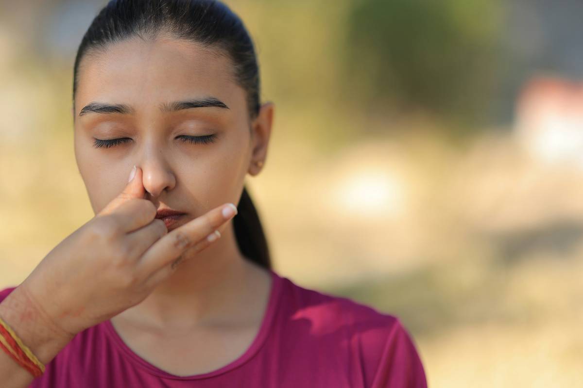 Woman practicing how to do 4-7-8 breathing while seated calmly with eyes closed, hands resting on knees